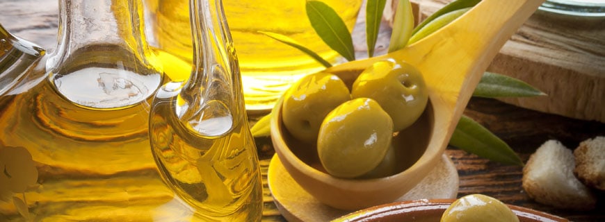 Olivenöl und Oliven im Holzlöffel