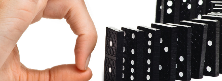eine Hand dabei eine Dominoreihe umzustossen 
