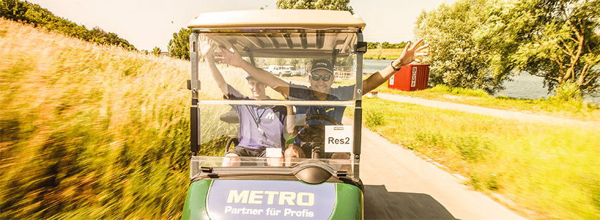 Metro-Golfcar mit zwei Personen aus dem Team