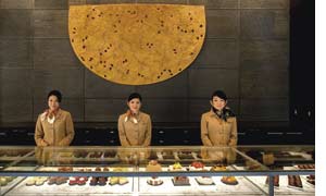 drei Mitarbeiterinnen eines Hotels in Japan hinter einer Theke unter der sich japanische Köstlichkeiten verbergen 