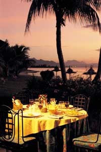 ein rosaroter Himmel, eine Palme und ein romantisch eingedeckter Tisch auf Mauritius 