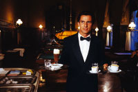 Ein Kellner im Anzug trägt diverse Heißgetränke und ein Bier 