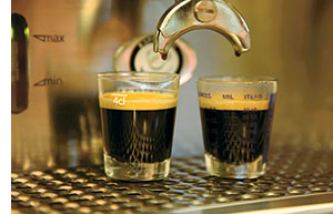 zwei Espressos werden aus der Kaffeemaschine heruntergelassen 
