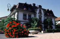 das Restaurant von Philippe Rochat, das ehemalige Rathaus, ein weißes Haus mit einem Brunnen und blühenden Sträuchen 