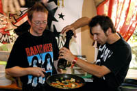 zwei Herren in Ramones T-Shirts würzen ein Pfannengericht 