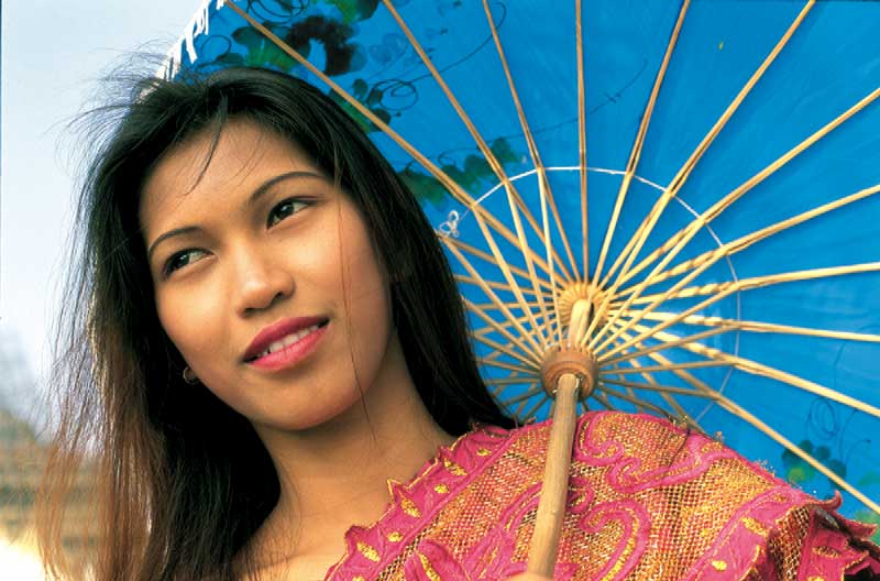 eine vietnamesische frau bunt gekleidet mit einem Sonnenschirm 