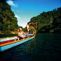 ein Paar sitzt in einem Holzboot und genießt die Sonnenstrahlen 
