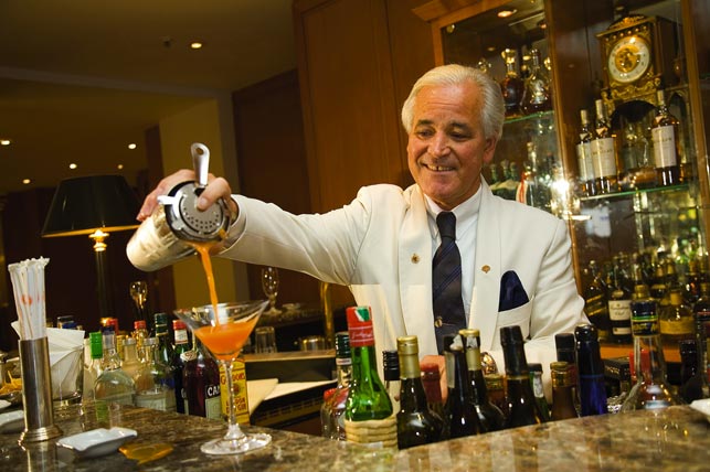 ein Barkeeper füllt den Cocktail vom Shaker ins Glas 