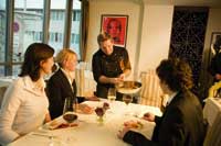 ein Kellner präsentiert einem Tisch mit zwei Damen und einem Herrn die Köstlichkeiten 