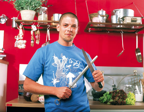 Tim Mälzer schärft ein Messer in der Küche