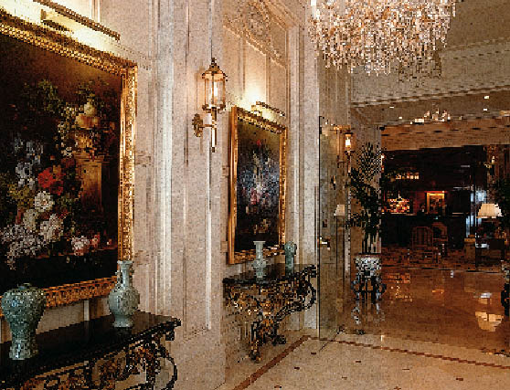 ein Raum mit französischen Möbeln ist zu sehen, an den Wänden hängen Gemälde von Blumenarragements und ein großer Kronleuchter ziert den Raum 