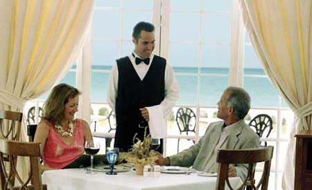 Ein Kellner begrüßt ein Paar am Esstisch mit Aussicht an den Stand