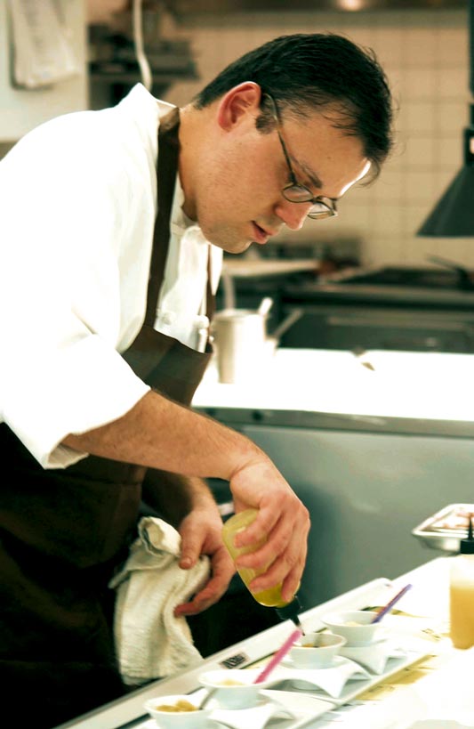 Ein Koch arbeitet mit einer Saucenspritze und verfeinert sein Gericht 