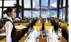 Eine Kellnerin in einem Alpenrestaurant mit Panoramablick auf die Berge 