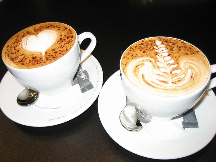 zwei Tassen Kaffee mit Herzchen im Kaffeeschaum 