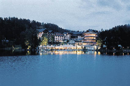 Hotel am See in der Abenddämmerung in einem Meer aus lichtern die sich im See wiederspiegeln 