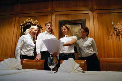 ein Herr und drei Damen besprechen den Plan der Abendgestaltung, alle tragen weiße Hemden 