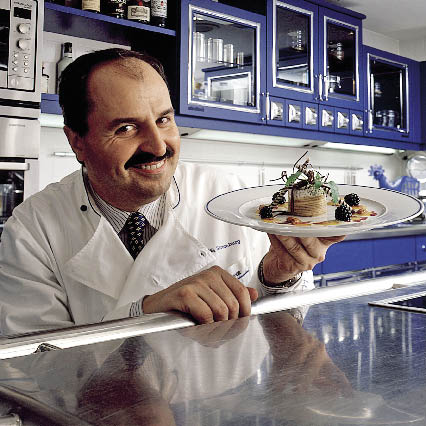 Johann Lafers mit einem Teller in der Hand in seiner Küche 