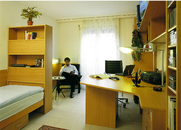Ein mann sitzt in einem mit Holzmöbel verkleidetem Raum und liest