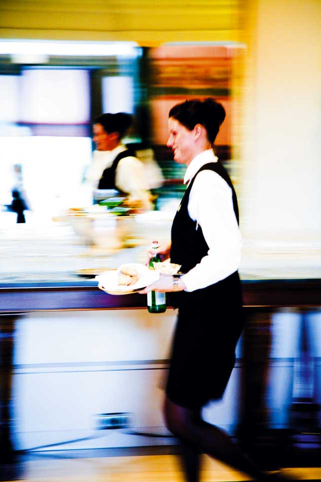 Eine Kellnerin trägt Essen und trinken während sie geht 
