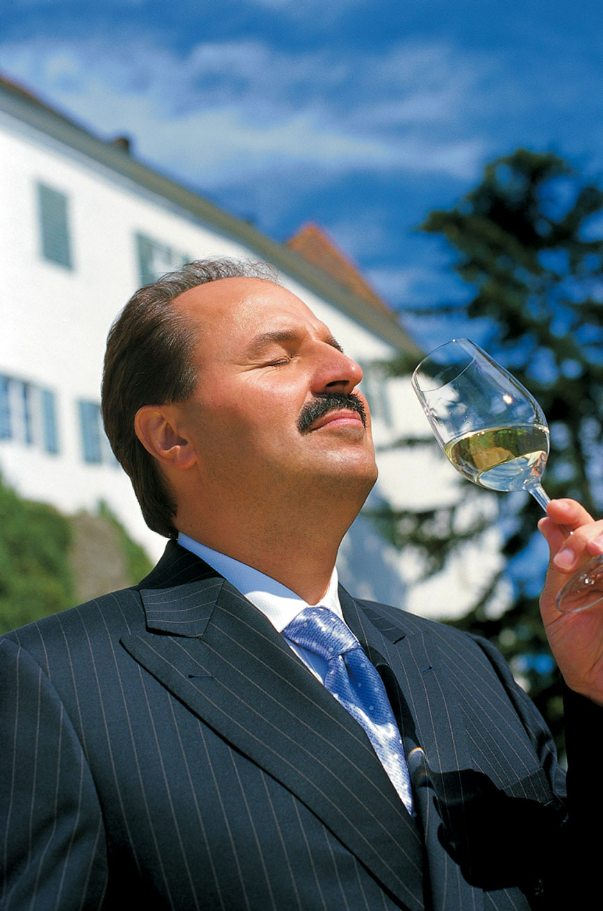 Johann Lafer genießt einen schluck weißwein im sonnenschein 