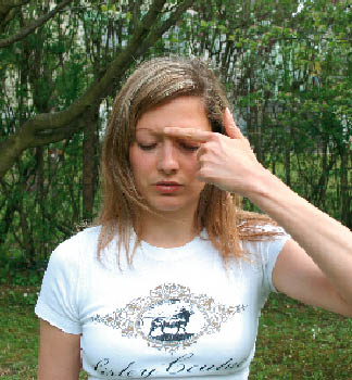 eine Dame demonstriert Entspannungsübungen, in diesem Fall mit dem Zeigefinger zwischen die Augenbrauen drücken 