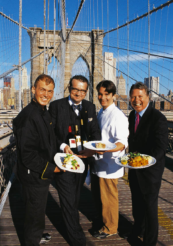 vier Herren stehen auf der Brooklyn Bridge in New York mit Tellern gefüllt mit kulinarischen Köstlichkeiten 