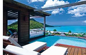 karibisches Paradies, weisse Sonnenliegen, ein Pool mit Ausblick aufs Meer, luxurioese Unterkunft