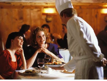 zwei damen sitzen in einem restaurant, während der koch ihnen die speise bringt himmeln sie ihn an 