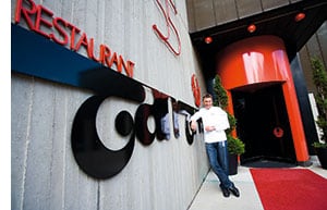 Hans Haas vor dem Logo ueber der Eingangstuer seines Restaurants