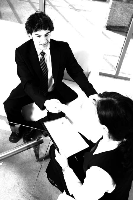 Ein Handschlag zwischen einer Frau und einem Mann, sitzend während eines Bewerbungsgespräches 