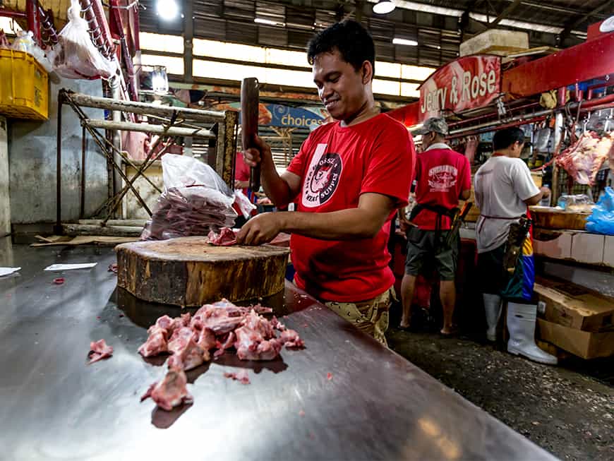 Filipinos am Marktstand beim Zerteilen von Fleisch